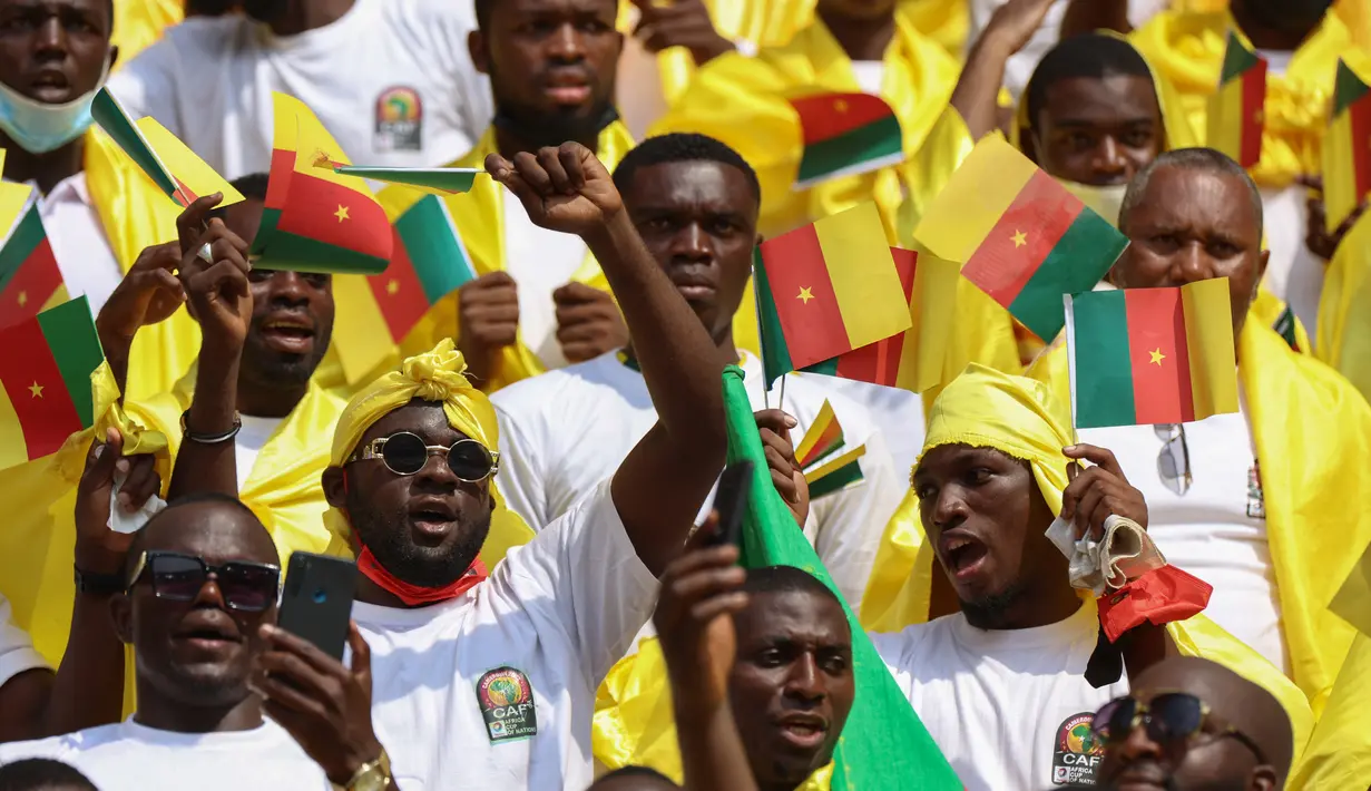 Sejumlah Suporter Kamerun bersorak menjelang upacara pembukaan turnamen Piala Afrika (CAN) 2021 di Stade d'Olembé di Yaounde (9/1/2022). Piala Afrika 2021 seharusnya digelar Januari 2021 tapi kemudian diundur karena pandemi. (AFP/Kenzo Tribouillard)