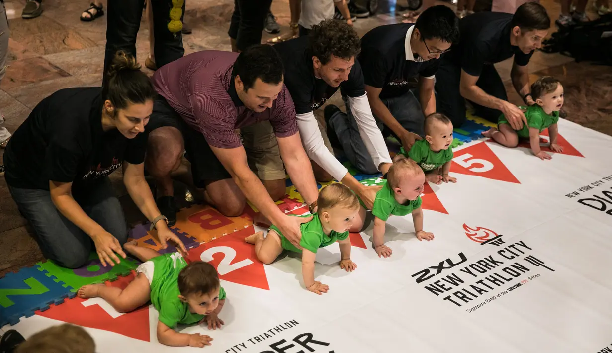 Sejumlah bayi bersiap digaris mulai untuk mengikuti lomba merangkak dalam Diaper Derby NYC triathlon di New York City (14/7). Lomba yang diikuti para bayi ini banyak mengundang tawa para orang tua dan penonton yang hadir. (AFP Photo/Dominick Reuter)
