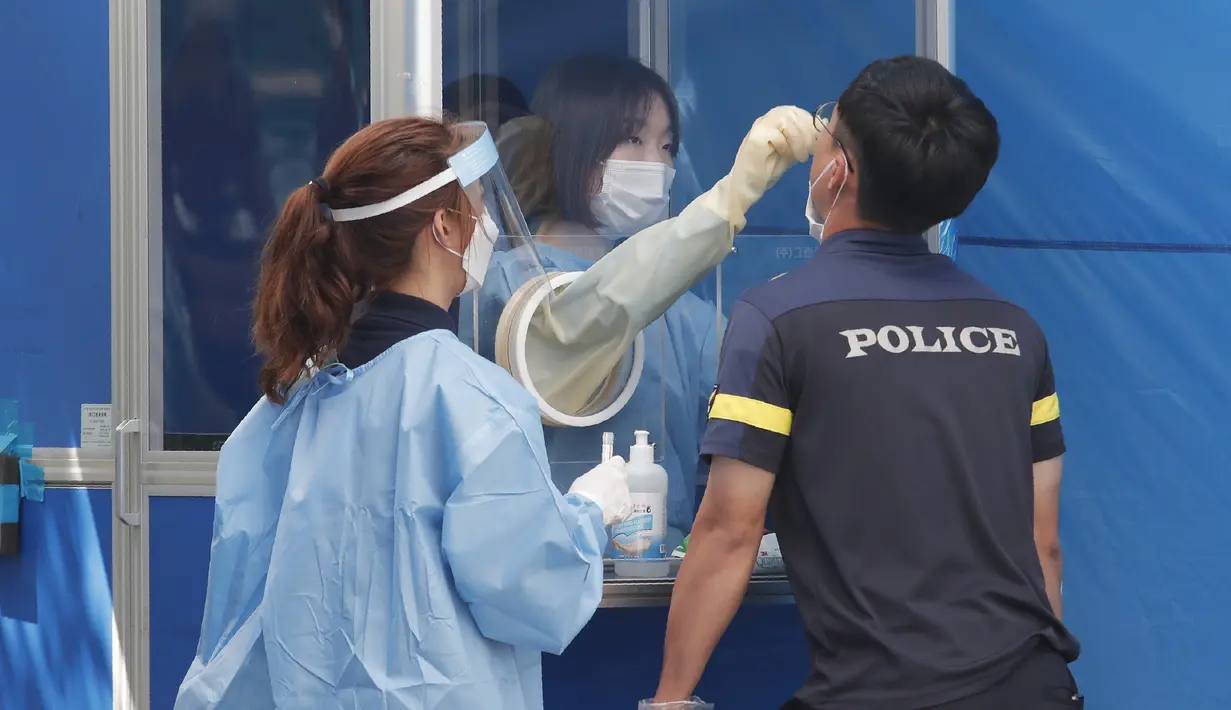 Seorang petugas medis mengambil sampel dari petugas polisi selama pengujian COVID-19 di Badan Kepolisian Metropolitan Seoul di Seoul, Korea Selatan, Rabu, (19/8/2020). (AP Photo / Ahn Young-joon)