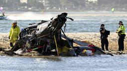 Petugas darurat memeriksa helikopter di lokasi tabrakan dekat Seaworld, di Gold Coast, Australia, Senin, 2 Januari 2023. Dua helikopter bertabrakan di udara menewaskan empat orang termasuk sepasang suami istri dari Inggris dalam kecelakaan yang menarik bantuan darurat dari pengunjung pantai selama musim panas. (Dave Hunt/AAP Image via AP)