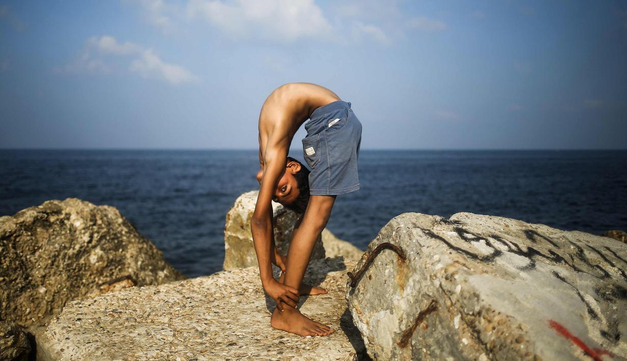 Yousef Al-Bahtini memperlihatkan keahlian akrobatiknya di pelabuhan Kota Gaza (20/9). Bocah Palestina ini siap memecahkan waktu tercepat rekor Guinness World Records dengan melakukan perjalanan 20 meter dalam kelenturan tubuh. (AFP Photo/Mohammed Abed)