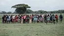 Orang Maasai melihat para pelari mengikuti kompetisi Olimpiade Maasai 2018 Kimana, Kenya (15/12). Olimpiade ini inisiatif dari kelompok konservasi internasional yang dipimpin oleh Born Free. (AFP Photo/Yasuyoshi Chiba)