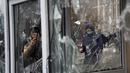 Seorang pria mengambil foto dari jendela kios polisi yang dirusak oleh demonstran selama protes di Almaty, Kazakhstan, Rabu (5/2/2022). Demonstran yang menolak kenaikan harga gas cair bentrok dengan polisi di kota terbesar Kazakhstan dan mengadakan protes di sekitar kota. (AP Photo/Vladimir Tretyako