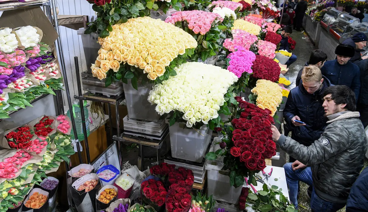 Pedagang bunga melayani pembeli jelang Hari Perempuan Internasional di pasar bunga di Moskow, Rusia (5/3). Hari Perempuan Internasional secara resmi dijadikan sebagai hari libur nasional di Soviet Rusia pada tahun 1917. (AFP Photo/Kirill Kudryavtsev)