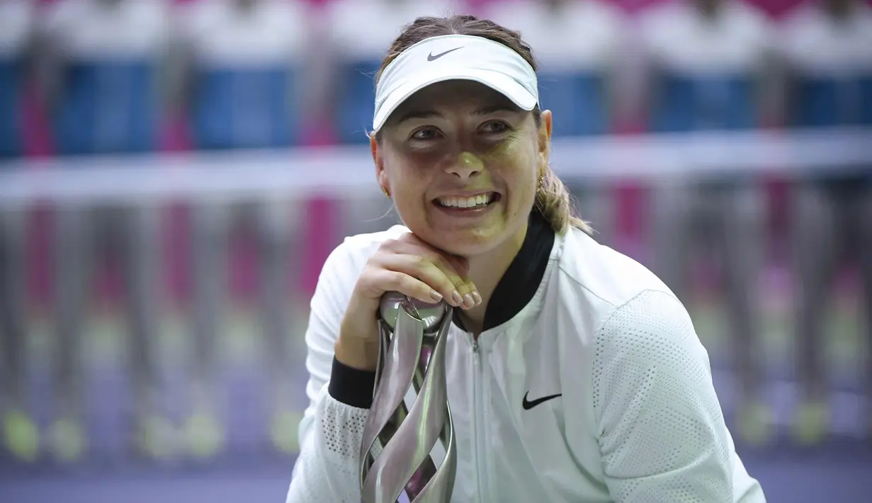 Senyum Maria Sharapova saat berpose dengan trofi setelah memenangkan pertandingan melawan Aryna Sabalenka di turnamen tenis Tianjin Open di Tianjin (15/10). Sharapova menang 7-5 7-6 atas Sabalenka. (AFP Photo/Wang Zhao)