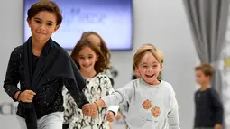 Seorang anak laki-laki dengan down syndrome berjalan di atas catwalk selama pekan mode Petite Fashion Week di Madrid, 6 Oktober 2017. Penampilan dan gaya model mungil  yang menggemaskan dan ekspresif itu mencuri perhatian penonton. (GABRIEL BOUYS/AFP)