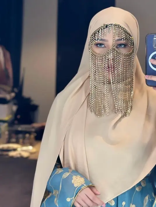 Dara Arafah tampil menawan mengenakan abaya warna biru muda yang dipadukan hijab warna krem dan chain face mask ala Arab sebagai aksesori. [@daraarafah]