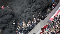 Penonton diselimuti asap hitam tebal saat pertandingan sepak bola PSV Eindhoven vs Ajax di Stadion Philips, Belanda (23/4). Asap tebal itu memaksa wasit untuk menunda pertandingan selama beberapa menit. (Olaf KRAAK / ANP / AFP)