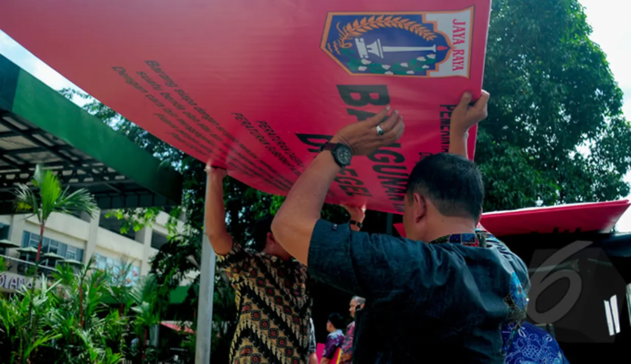 Petugas Penataan Kota DKI Jakarta membawa spanduk segel Mal Tebet Green karena belum memiliki sertifikat Surat Layak Fungsi (SLF), Jakarta, Kamis (5/3/2015). Penyegelan ini merupakan peringatan ketiga untuk mal Tebet Green. (Liputan6.com/Yoppy Renato)