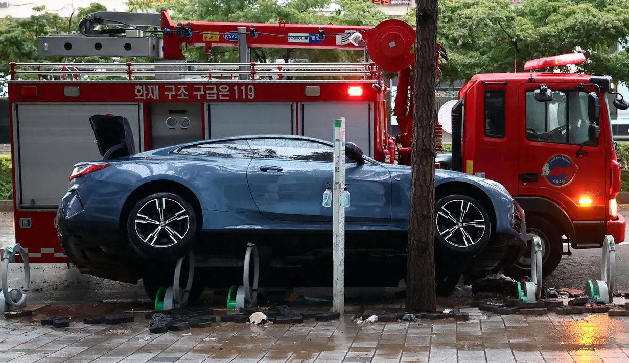 Sebuah mobil yang rusak akibat banjir terlihat di jalan setelah hujan deras di distrik Gangnam, Seoul pada Selasa (9/8/2022). Penduduk di daerah dataran rendah dievakuasi untuk keselamatan sementara bagian dari jalur kereta bawah tanah terpaksa berhenti.  (YONHAP / AFP)