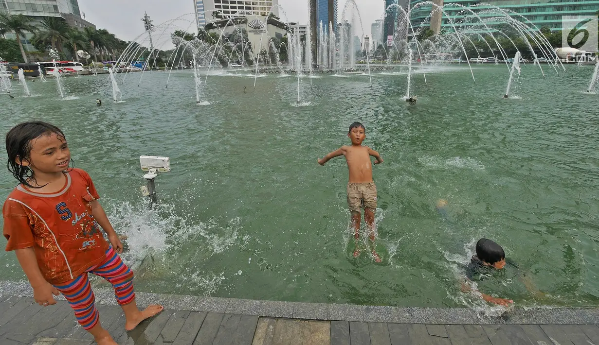 Seorang anak melompat ke kolam di Bundaran HI, Jakarta, Senin (17/6/2019). Meski ada larangan berenang, sejumlah anak tetap nekat menyebur ke kolam Bundaran HI. (Liputan6.com/Herman Zakharia)