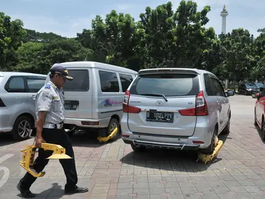 Sejumlah mobil hasil razia dan ban tergembok terparkir di IRTI Monas, Jakarta, Senin (13/3). Pada periode Januari-Febuari, Dishub menindak 6.437 kendaraan dengan sanksi ditilang. (Liputan6.com/Yoppy Renato)