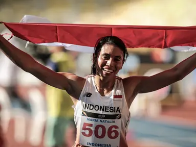 Atlet Lompat Jauh Indonesia, Maria Natalia Londa membawa bendera Merah Putih usai berlaga di nomor triple jump putri SEA Games di Stadium Bukit Jalil, Malaysia, Rabu (23/8). (Liputan6.com/Faizal Fanani)