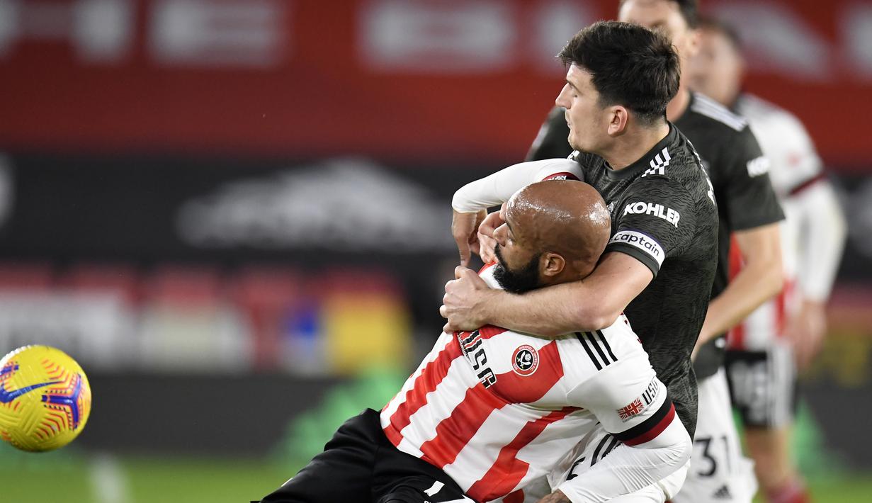 Bek Manchester United, Harry Maguire (kanan), menempel ketat striker Shefffield United, David McGoldrick, dalam laga lanjutan Liga Inggris pekan ke-13 di Bramall Lane, Sheffield, Kamis (17/12/2020). Manchester United menang 3-2 atas Sheffield United. (AFP/Peter Powell/Pool)