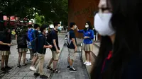 Siswa dengan mengenakan masker antre untuk memeriksa suhu mereka di sekolah Marie Curie di Hanoi, Senin (4/5/2020). Vietnam membuka kembali aktivitas sekolah yang ditutup selama tiga bulan setelah dilaporkan tidak ada kasus virus corona COVID-19 baru hingga Sabtu, 2 Mei 2020. (Manan VATSYAYANA/AFP)