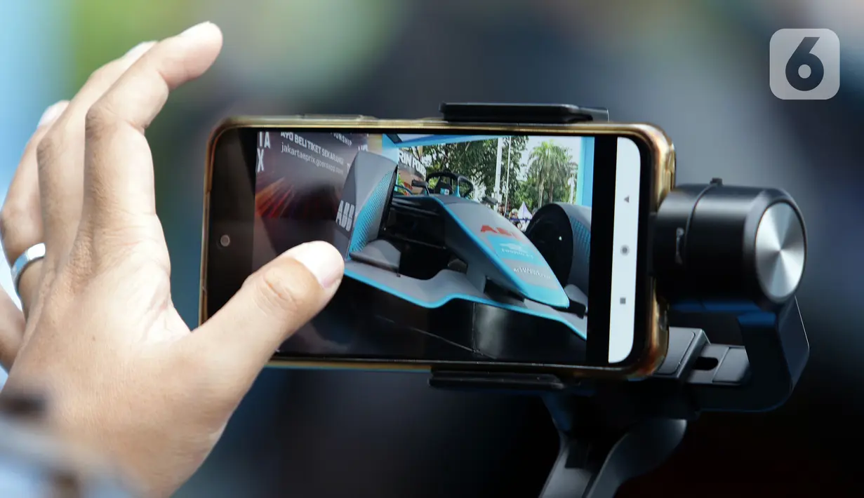 Warga merekam replika mobil Formula E yang dipamerkan di Kawasan Bundaran Hotel Indonesia, Jakarta, Minggu (29/5/2022). Replika mobil balap ramah lingkungan ini dipamerkan untuk mengkampanyekan perhelatan Formula E yang akan digelar 4 Juni mendatang. (Liputan6.com/Helmi Fithriansyah)