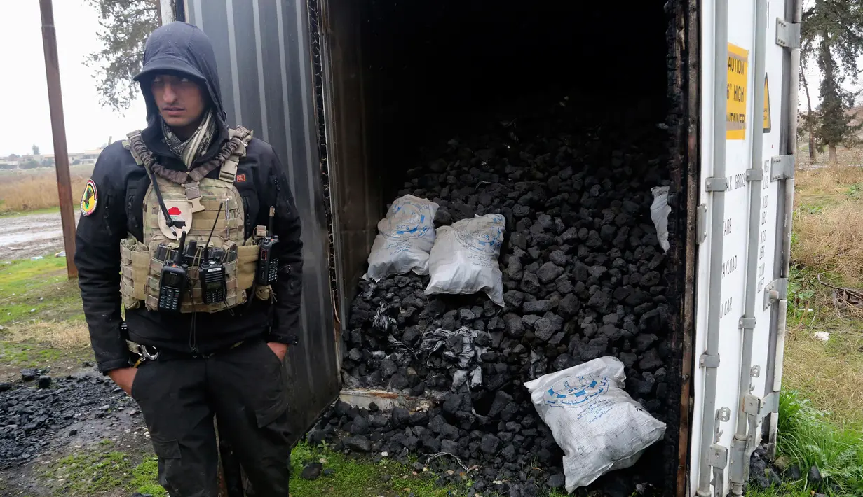 Seorang pasukan khusus Irak berdiri dekat kontainer berisi gas mustard yang ditemukan di sebuah gudang senjata di sisi timur Mosul, Sabtu (28/1). Pihak berwenang mengatakan bahwa gudang senjata itu milik kelompok militan ISIS. (AP Photo/Khalid Mohammed)