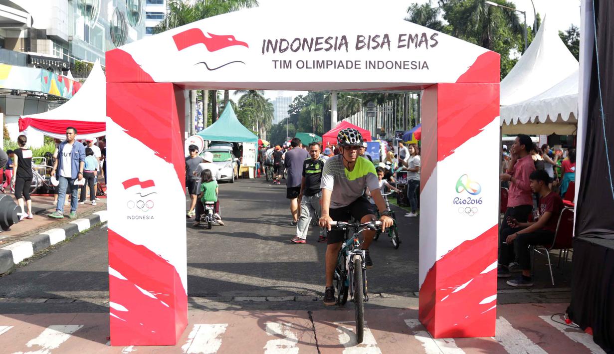 Warga melintas deket gapura kampanye Indonesia Bisa Emas, Road to Rio 2016 di Senayan, Jakarta, Minggu (20/3/2016). (Bola.com/Nicklas Hanoatubun)