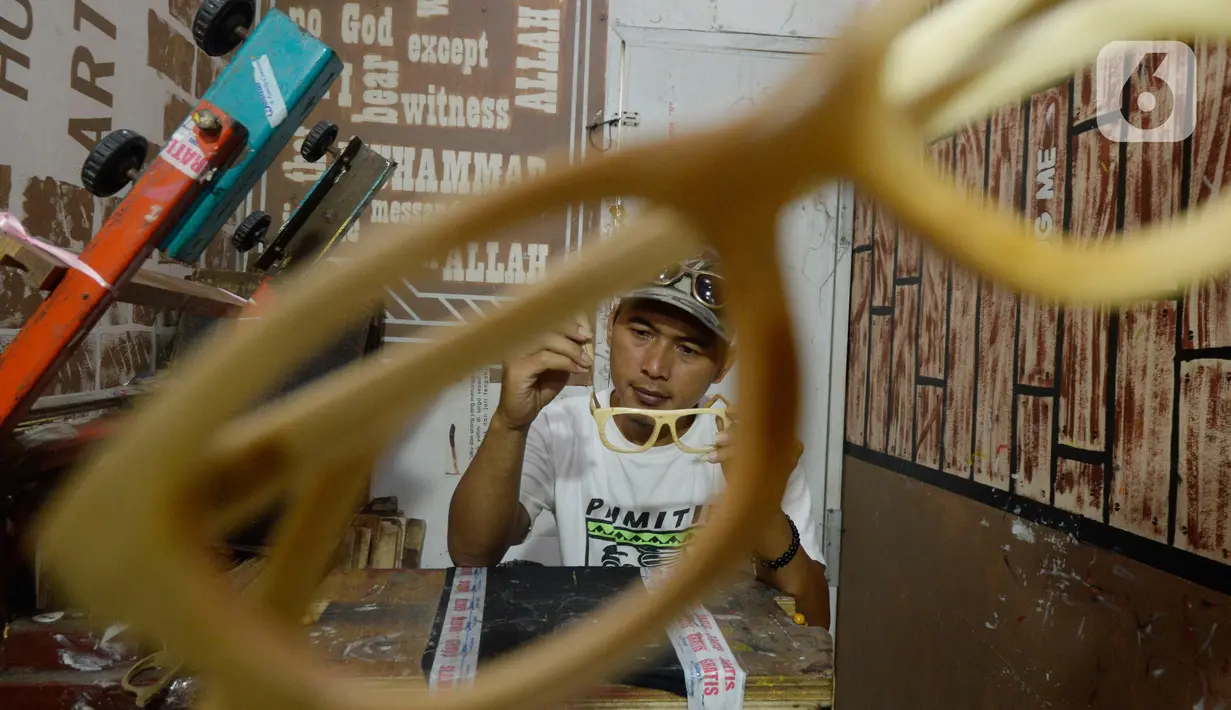 Perajin Yuyud Wahyudi (39) menyelesaikan pembuatan frame kacamata dari limbah kayu bekas di Urat Kayu, Pondok Benda, Pamulang, Tangsel, Kamis (8/10/2019). Kacamata kayu hasil buatannya tersebut dijual dengan harga Rp 300 ribu hingga Rp 1,2 juta per buah. (merdeka.com/Dwi Narwoko)