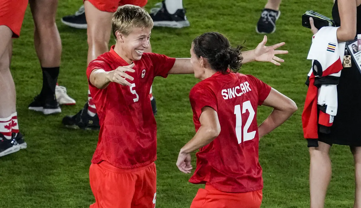 Pesepak bola Kanada Quinn (kiri) dan Christine Sinclair berselebrasi setelah mengalahkan Swedia dalam adu penalti sepak bola putri Olimpiade Tokyo 2020 untuk medali emas di Yokohama, Jepang pada 6 Agustus 2021. Quinn jadi atlet transgender pertama yang memenangkan medali Olimpiade (AP/Kiichiro Sato)