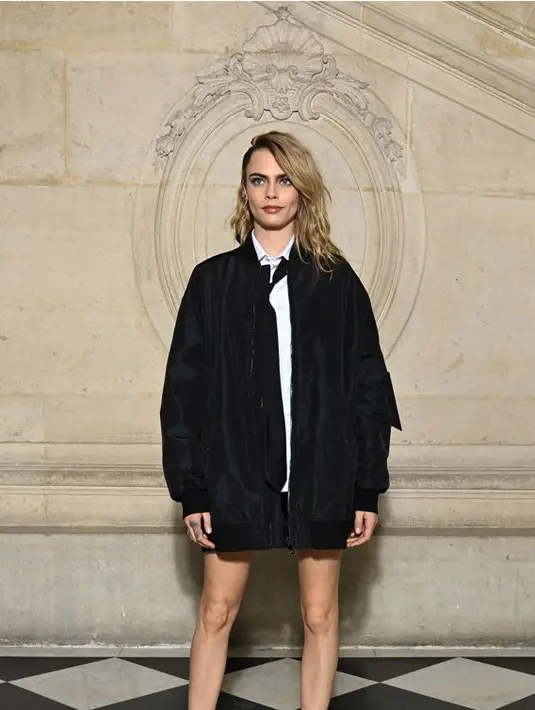 Salah satunya Cara Delevingne. Aktris dan penyanyi ini tampil edgy di Paris Fashion Week dalam balutan jaket bordir hitam Dior Pre Fall 2022 dengan kemeja katun putih dan celana pendek wol dan sutra hitam. Dia juga mengenakan dasi hitam dan sepatu hitam. (Dior)