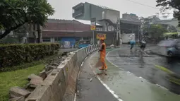 Petugas PPSU membersihkan sampah dekat beton pembatas di Jalan Senopati, Jakarta, Minggu (29/12/2019). Pascakejadian mobil tabrak Apotek Senopati, Suku Dinas Bina Marga memasangan beton pembatas untuk meminimalisir kejadian serupa terulang kembali. (Liputan6.com/Faizal Fanani)