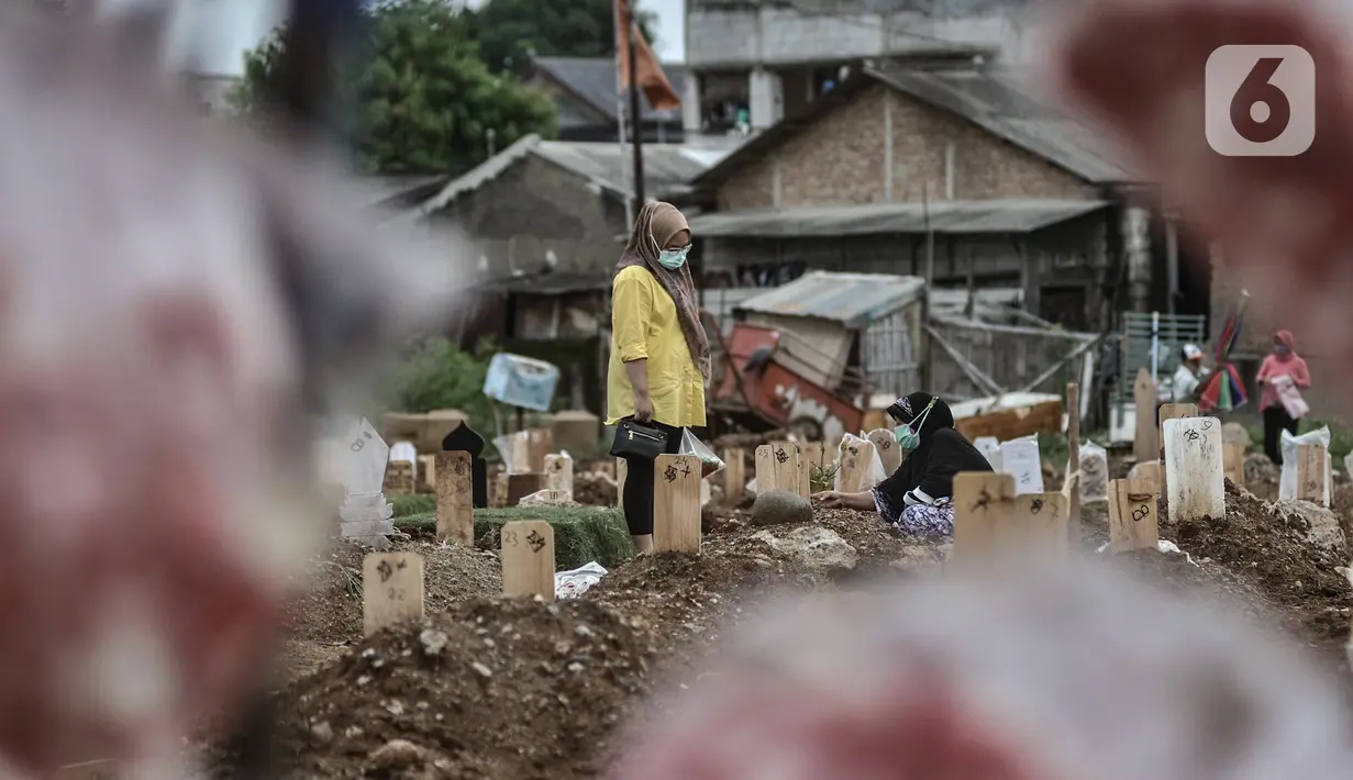 Warga berziarah ke makam anggota keluarga yang dikebumikan dengan protokol Covid-19 di TPU Tegal Alur, Jakarta, Kamis (14/1/2021). Hingga saat ini tercatat sebanyak 4.500 jenazah terkait Covid-19 telah dimakamkan di blok muslim TPU Tegal Alur. (merdeka.com/Iqbal S. Nugroho)