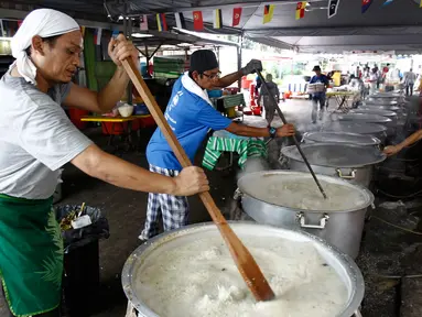 Sejumlah orang mengaduk Bubur Lambuk di desa Kampung Baru, Kuala Lumpur, Malaysia, Kamis (1/6). Bubur Lambuk adalah bubur yang terbuat dari beras dengan campuran rempah dan sayuran. (AP/Daniel Chan)