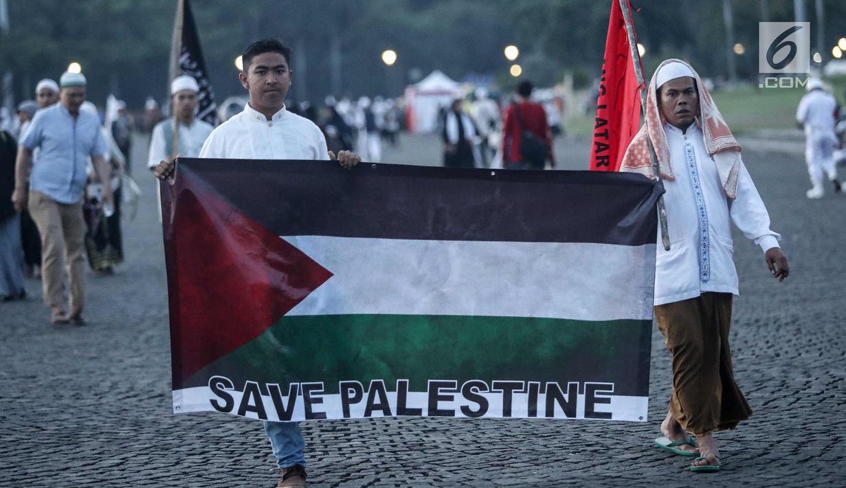 Peserta Aksi membawa bendera Palestina di kawasan silang Monas, Jakarta, Minggu (17/12). Massa dari berbagai daerah ini datang atas ajakan Majelis Ulama Indonesia (MUI). (Liputan6.com/Faizal Fanani)