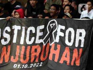 Pendukung timnas Indonesia membentang spanduk bertuliskan “Justice for Kanjuruhan” saat menyaksikan laga kualifikasi Grup A Piala AFF 2022 antara Indonesia melawan Kamboja di di Stadion Utama Gelora Bung Karno, Jakarta, Jumat (23/12/2022). Mereka menyuarakan pengusutan tuntas kasus atas Tragedi Kanjuruhan yang terjadi pada awal Oktober 2022 lalu. (Liputan6.com/Helmi Fithriansyah)