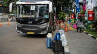 Seorang warga dengan barang bawaannya menunggu untuk menaiki bus mudik bareng gratis BUMN di kawasan Jakarta, Rabu (27/4/2022). Program mudik gratis merupakan salah satu solusi untuk mengantisipasi potensi kepadatan lalu lintas pada masa Lebaran.(Liputan6.com/Faizal Fanani)