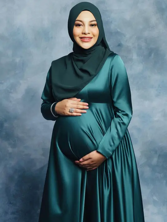 Maternity shot Aurelie Hermansyah dengan makeup bernuansa oranye. Tampilan kontras dengan satin dress bernuansa hijau membuatnya tampak memukau. Foto: Instagram.