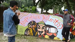 Pengunjung berpose di salah satu lukisan mural saat Festival Budaya Betawi Rupa-Rupa Jakarta di Zona A Setu Babakan, Jakarta, Rabu (14/9). Festival ini menampilkan berbagai kegiatan bernuansa Betawi. (Liputan6.com/Immanuel Antonius)