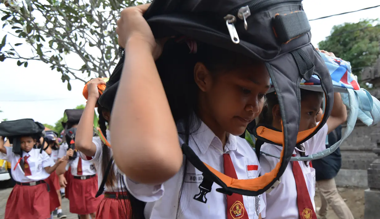 Sejumlah siswi SD menggunakan tas sekolah mereka untuk melindungi diri selama latihan tsunami di Tanjung Benoa dekat Denpasar di pulau resor Bali (15/8). (AFP Photo/ Sonny Tumbelaka)