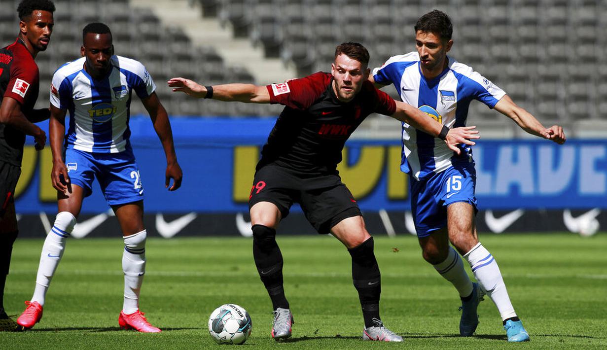 Pemain Hertha Berlin, Marko Grujic, berebut bola dengan pemain Augsburg, Eduard Lowen, pada laga Bundesliga di Olympiastadion, Sabtu (30/5/2020). Hertha Berlin menang 2-0 atas Augsburg. (AP/Hannibal Hanschke)