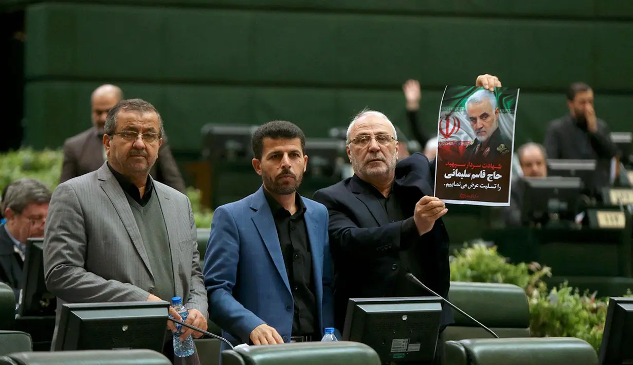 Anggota parlemen Iran memegang poster bergambar Jenderal Qasem Soleimani saat voting RUU yang menetapkan pasukan militer Amerika Serikat sebagai teroris, Teheran, Selasa (7/1/2020). Dalam RUU tersebut seluruh pihak terkait pembunuhan Soleimani ditetapkan sebagai teroris. (ICANA NEWS AGENCY/AFP)