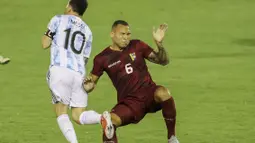 Lionel Messi mendapatkan tekel keras dari bek Venezuela, Luis Martinez. Martinez mengangkat kaki terlalu tinggi saat mencoba merebut bola dari kaki La Pulga.  (Foto: AFP/Miguel Gutierrez, Pool)
