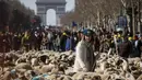 Gembala berdiri di antara sekitar 2.000 domba untuk menandai berakhirnya Pameran Pertanian Internasional di jalan Champs-Elysees Paris, Minggu (6/3/2022). Hewan dan gembala dari wilayah barat daya Prancis diarak di jalan terkenal mempromosikan pekerjaan dan wilayah mereka. (AP Photo/Thomas Padilla)