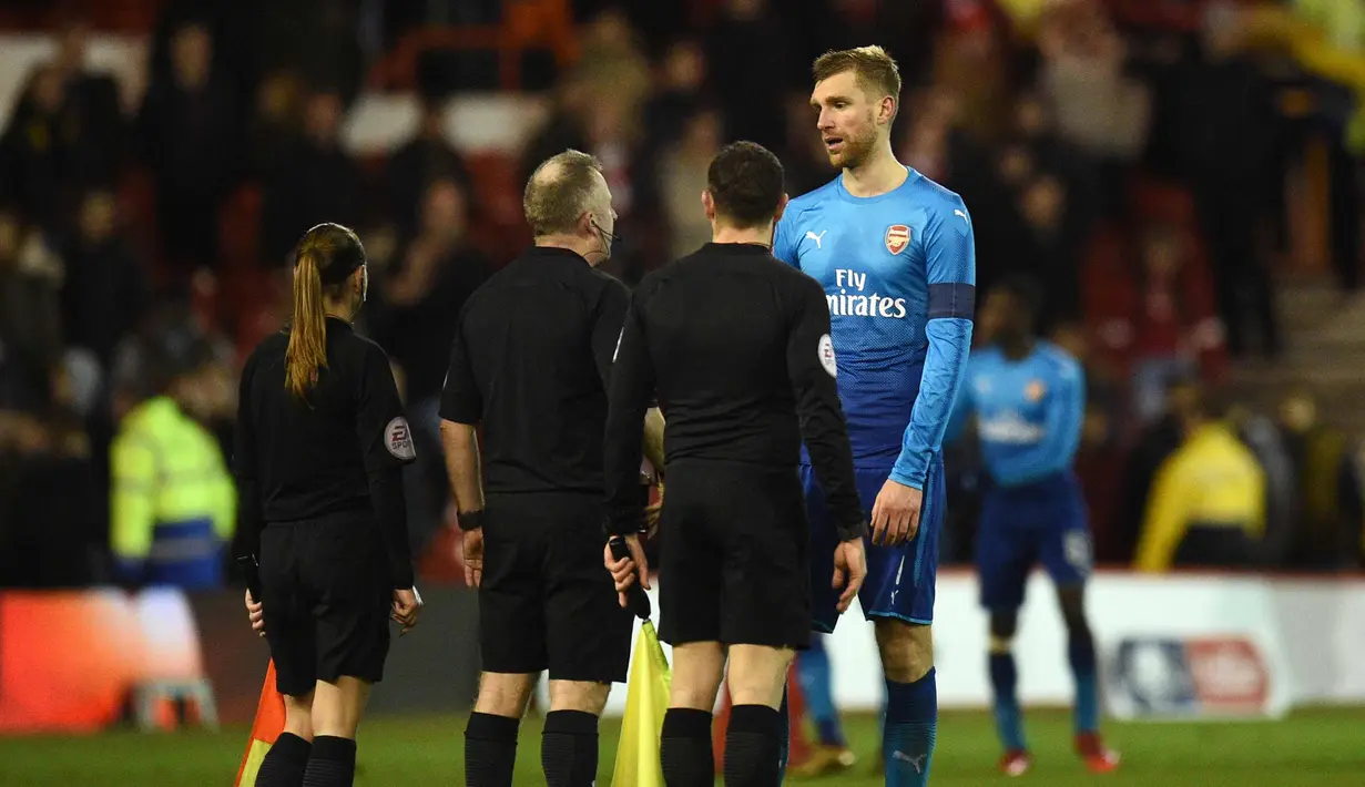 Bek Arsenal, Per Mertesacker (kanan) berbicara kepada wasit Jonathan Moss (kedua kiri) setelah pertandingan melawan Nottingham Forest di pertandingan babak ketiga Piala FA di City Ground, Nottingham, Inggris (7/1). (AFP Photo/Oli Scarff)
