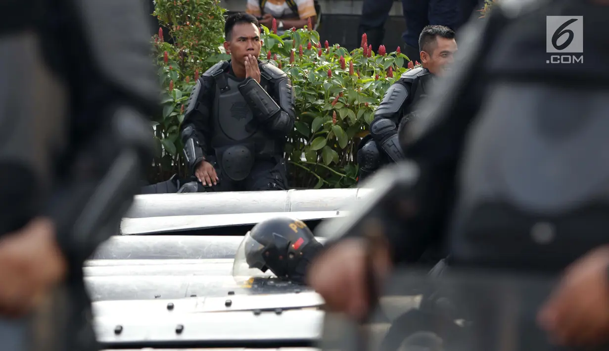 Anggota kepolisian dari satuan Brimob beristirahat saat menjaga aksi unjuk rasa yang dilakukan Gerakan Nasional Kedaulatan Rakyat di depan Gedung Bawaslu, Jakarta, Selasa (21/5/2019). Ribuan aparat keamanan gabungan diterjunkan untuk mengamankan jalannya aksi. (Liputan6.com/Helmi Fithriansyah)