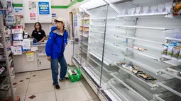 Rak-rak kosong terlihat saat pengunjung membeli  kebutuhan  di sebuah toko, distrik Shinagawa, Tokyo, Sabtu (12/10/2019). Banyak toko-toko perbelanjaan di Jepang yang kehabisan makanan dan minuman akibat warganya yang menimbun makanan untuk menghadapi topan Hagibis. (Odd ANDERSEN / AFP)