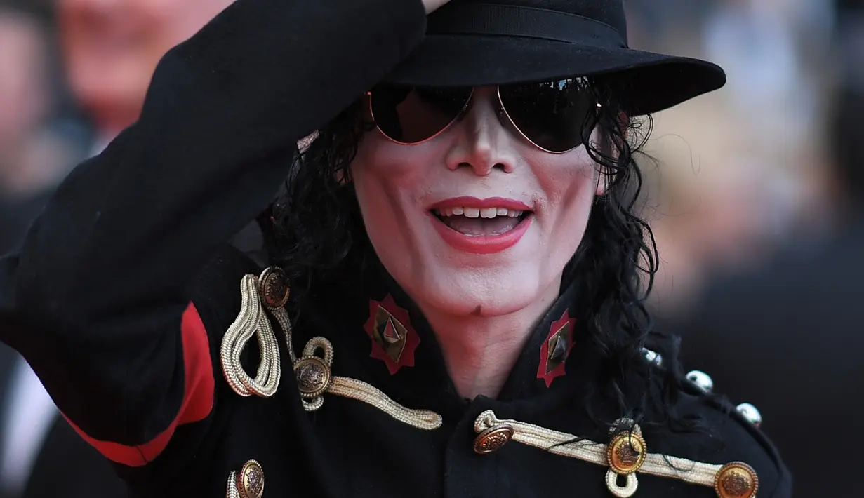Pria berpenampilan Michael Jackson berpose setibanya di karpet merah  pemutaran film Solo: A Star Wars Story pada Festival Film Cannes, Prancis, Selasa (15/5). Kehadiran pria mirip mendiang raja musik pop dunia itu mengundang perhatian. (AFP/LOIC VENANCE)