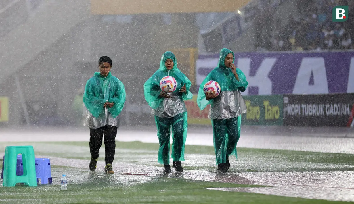 Sejumlah ball boy berjalan di bawah guyuran hujan dalam laga final Pegadaian Liga 2 2024/2025 antara Bhayangkara FC melawan PSIM Yogyakarta di Stadion Manahan, Solo, Jawa Tengah, Rabu (26/02/2025). (Bola.com/Abdul Aziz)