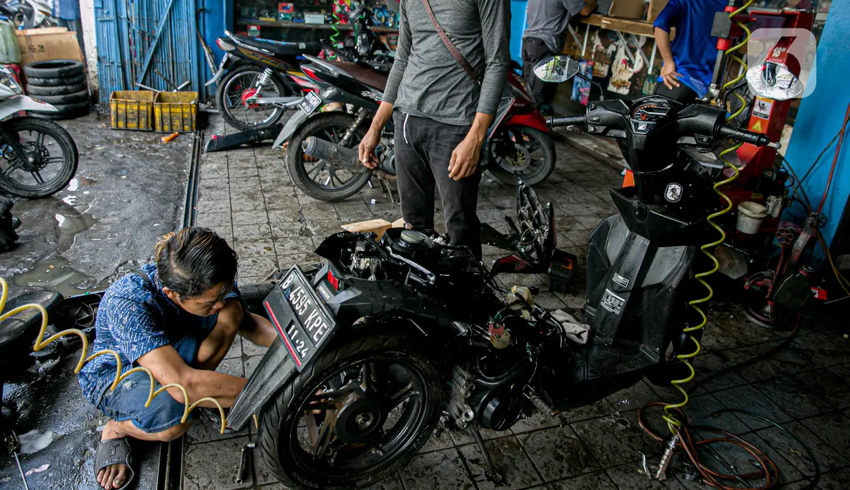 Montir memperbaiki sepeda motor konsumen usai terendam banjir di kawasan Mampang, Jakarta, Minggu (21/2/2021). Banjir yang melanda Ibu Kota Jakarta pada Sabtu (20/2) menyebabkan banyak kendaraan warga mengalami kerusakan akibat terendam air. (Liputan6.com/Faizal Fanani)