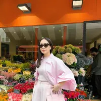 Menambah sentuhan playful, ia mengenakan kacamata hitam berbentuk hati dan menenteng tas tangan berwarna pink pastel dari koleksi kolaborasinya bersama brand lokal, Vone World. [@raffinagita1717].