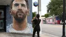 Seorang karyawan mengabadikan mural wajah Lionel Messi melalui gawainya yang berada di salah satu jalan di Miami, Amerika Serikat. Messi memutuskan untuk bergabung dengan klub MLS, Inter Miami, pada Rabu (7/6/2023). (AFP/Giorgio Viera)