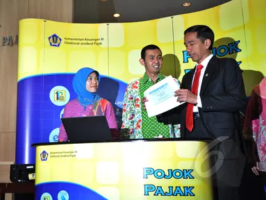 Presiden Joko Widodo (kanan) dibantu petugas mengisi surat pemberitahuan tahunan (SPT) pajak penghasilan menggunakan sistem e-filling di Kantor Pusat Ditjen Pajak Jakarta, Kamis (19/3/2015). (Liputan6.com/Faizal Fanani)