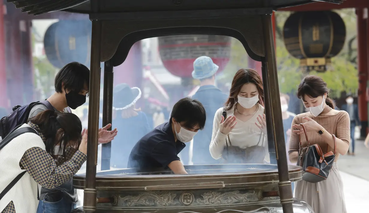 Pengunjung mengenakan masker wajah untuk melindungi dari penyebaran mandi virus corona di spanduk dupa di kuil Sensoji di distrik Asakusa di Tokyo, Rabu, Jepang (14/10/2020). Tokyo mengonfirmasi lebih dari 170 kasus virus corona baru pada hari Rabu. (AP Photo/Koji Sasahara)