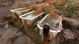 Seorang pengunjung bersantai di bak mandi yang berada di Mystic Hot Springs di Utah, Amerika Serikat. Bak mandi yang terletak di bukit ini sengaja dipasang oleh Mike Ginsburg yang saat itu sedang berlibur ketempat ini. (Dailymail.co.uk)