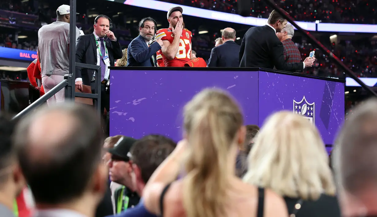 Pemain Kansas City Chiefs, Travis Kelce (atas) memberikan gestur kecupan jauh untuk kekasihnya, Taylor Swift setelah memenangkan Super Bowl LVIII di Las Vegas, Amerika Serikat, Minggu (11/02/2024) waktu setempat. Kansas City Chiefs menang atas San Francisco 49ers dengan skor 25-22 melalui babak tambahan. (AFP/Ezra Shaw)
